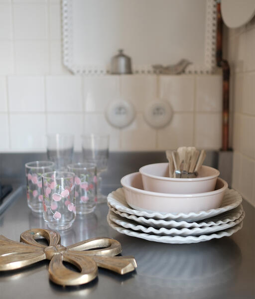 A stack of plates and glasses on a counter.
